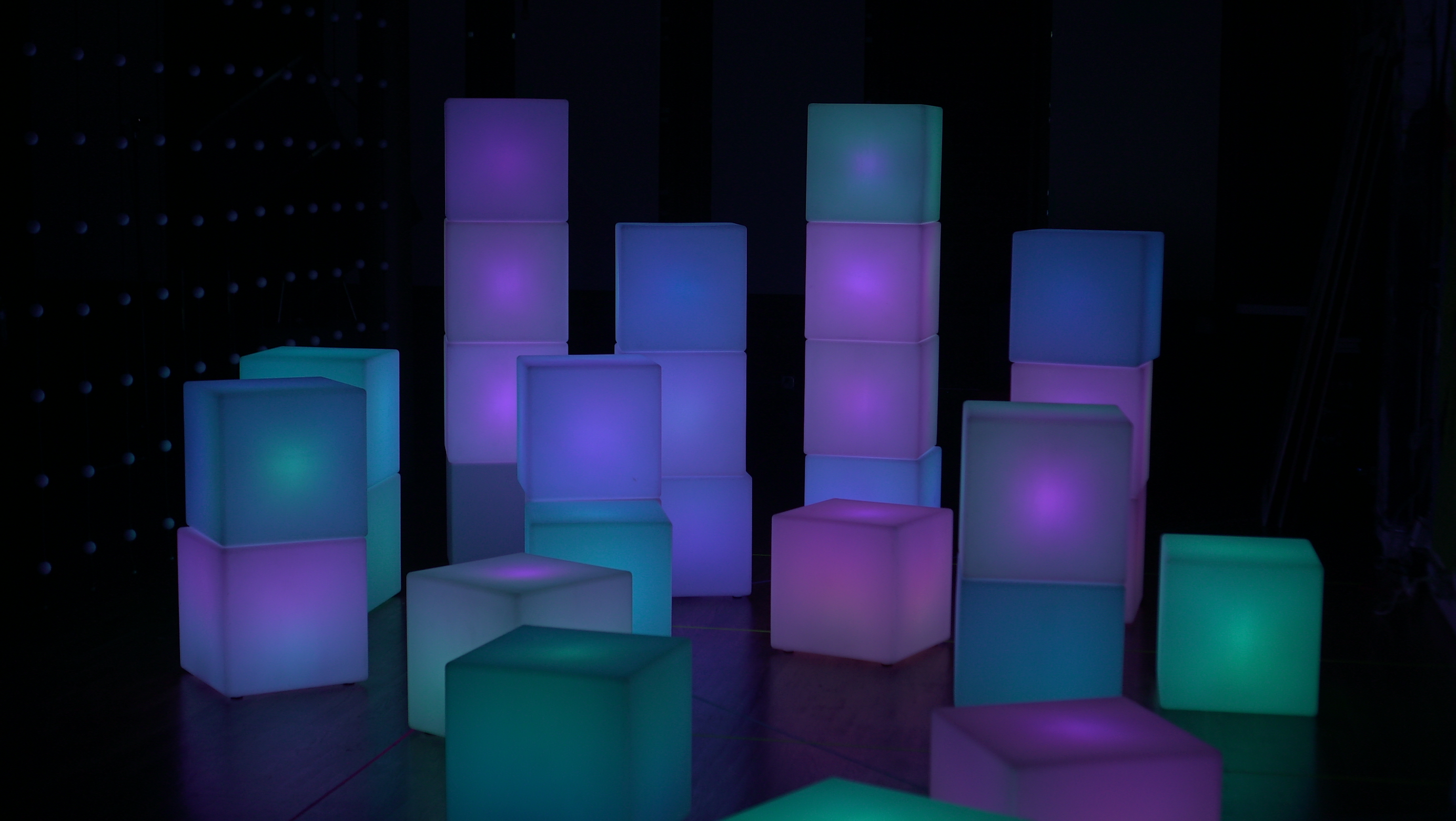 large glowing cubes stacked in columns of various heights between 1-4 cubes. Cubes glow various colors on a spectrum between cyan and purple.